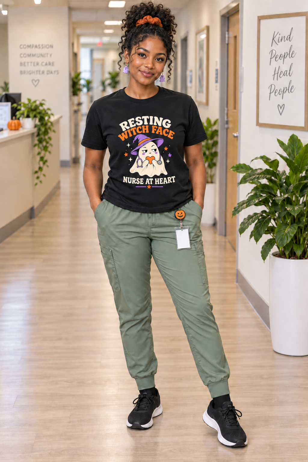 Nurse wearing a black Resting Witch Face, Nurse at Heart Halloween T shirt with sage scrub pants, pumpkin badge reel, orange scrunchie, black socks and trainers.