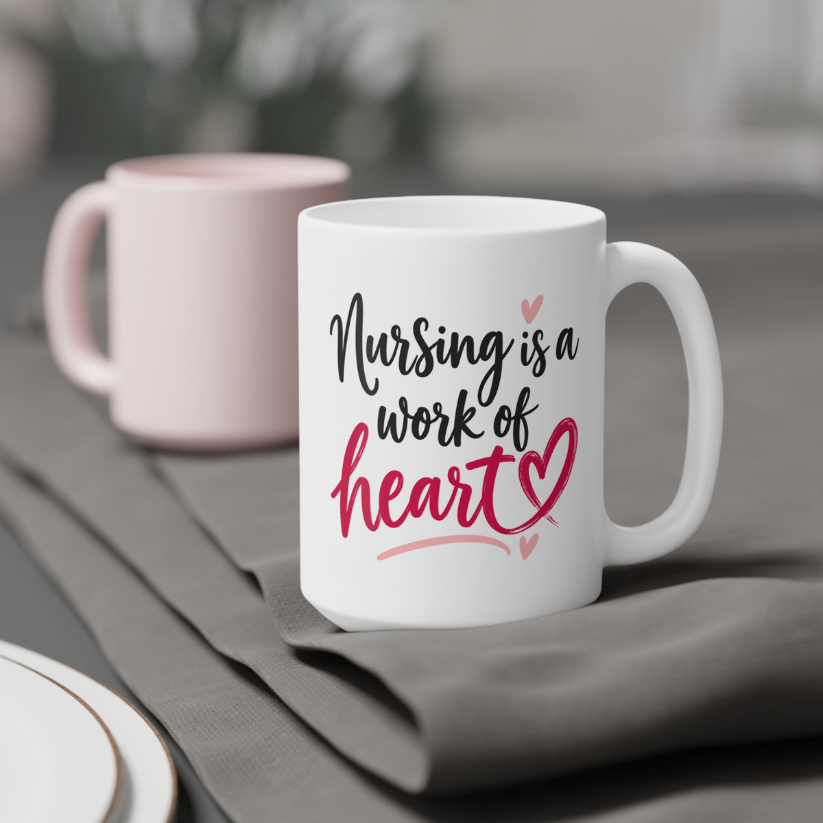 White 15oz ceramic mug with Nursing Is a Work of Heart lettering and raspberry heart, styled product view.