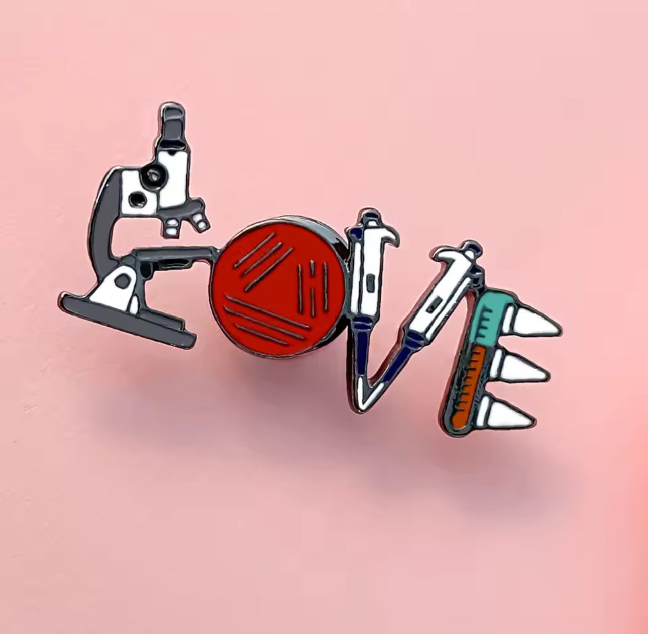 Science-themed LOVE enamel pin using a microscope, petri dish, pipette, and test tubes to spell the word.