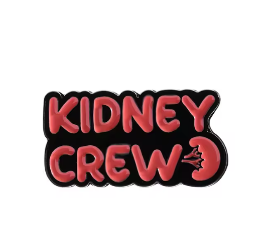 “Hard enamel pin with bold red bubble text saying ‘Kidney Crew’ and a stylized kidney illustration on a black background.”