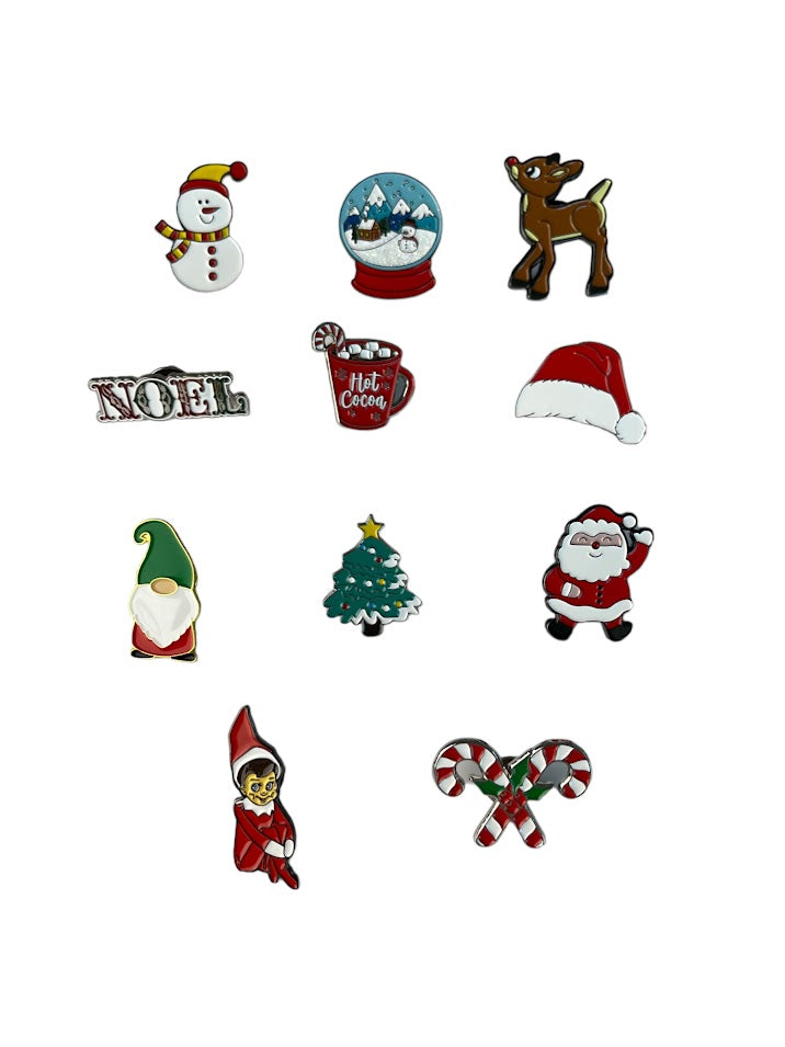 11 Christmas enamel pins of a snowman, snow globe, Rain deer, Noel, hot chololate, Santa hat, Gnome, Christmas tree, Snowman, Elf on the Shelf, and Candy Cane