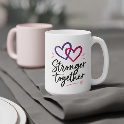 White 15oz ceramic mug with Stronger Together lettering and intertwined purple and raspberry hearts, styled product view.