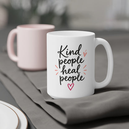 White 15oz ceramic mug with Kind People Heal People handwritten lettering and pink heart, styled product view.