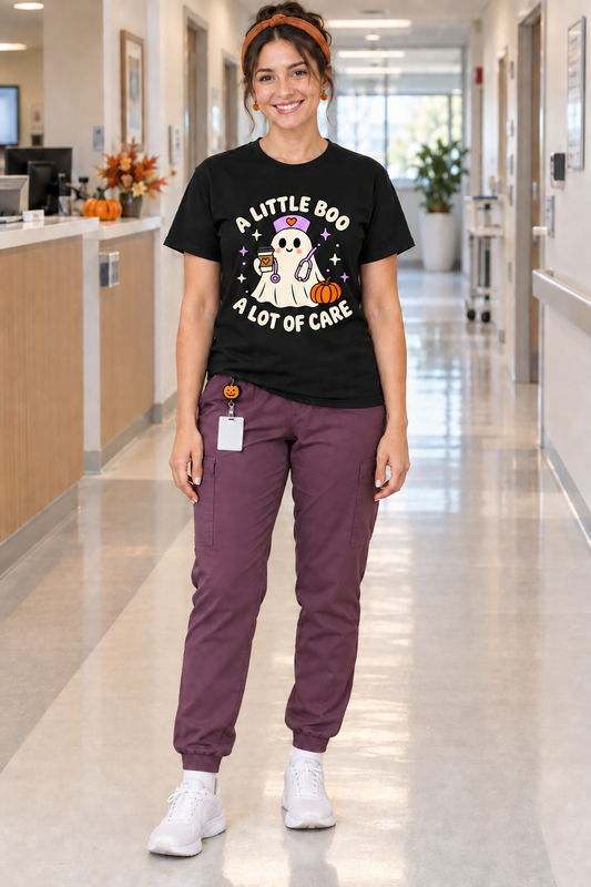 Nurse wearing a black A Little Boo, A Lot of Care Halloween T shirt with plum scrub pants, pumpkin badge reel, orange headband and white socks and sneakers.