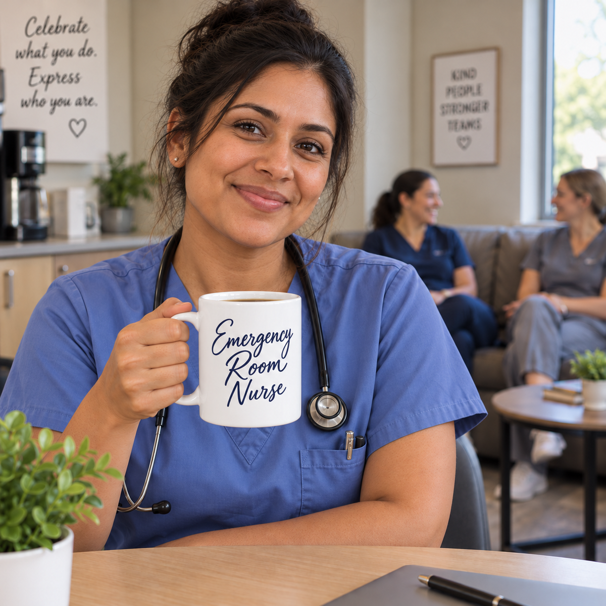 Nurse in blue scrubs holding a navy Emergency Room Nurse script mug at a break-room table, with two teammates on the couch behind her.