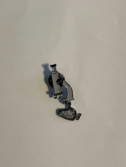 Microscope enamel pin in grey with smiling cell detail