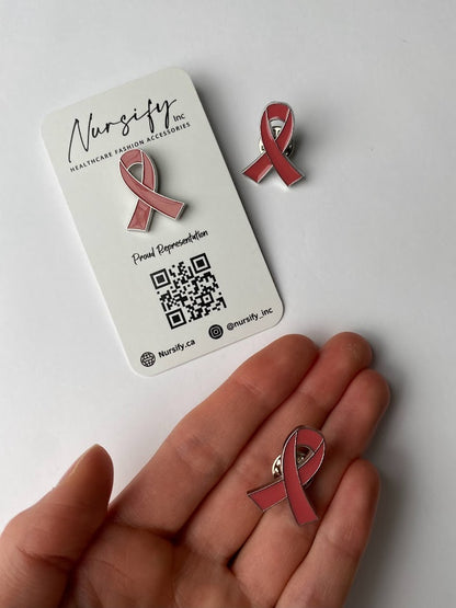 Pink breast cancer ribbon enamel pin | size shown compared to an average-sized woman’s hand