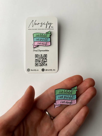 I AM… enamel pins with motivational quotes. Hard enamel with rubber clutch backing. Suitable for jackets, bags, lanyards, or clothing. Size shown compared to hand.