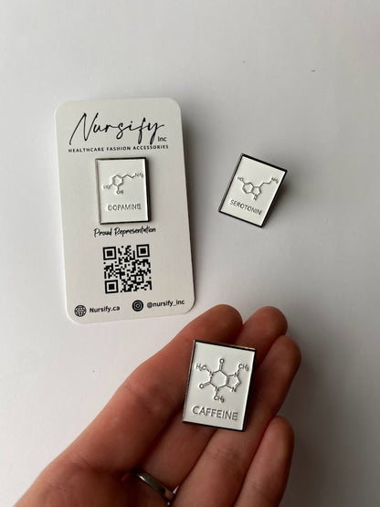 Chemical structure enamel pins for caffeine, dopamine, and serotonin on a white background | size shown compared to an average-sized woman’s hand