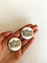 Two Wild About Nursing button pins shown in a hand for scale