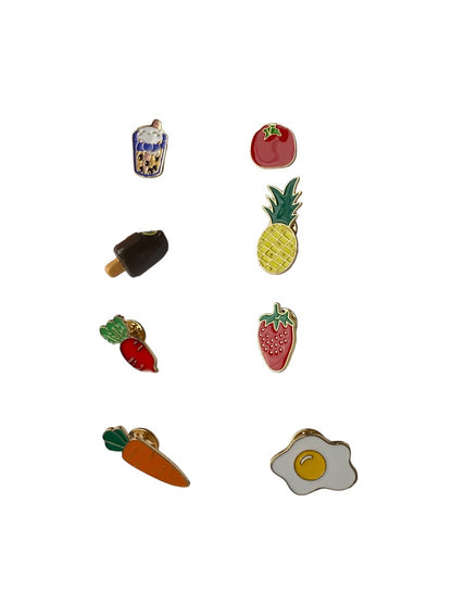 an assortment of food pins specifically a Tomato pin, Pineapple pin, Strawberry pin, Fried egg, Carrot pin, Beet pin, Boba pin and a Fudgesicle pin. 
