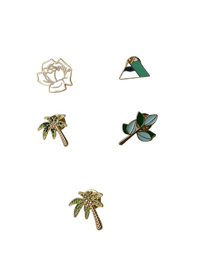 a photo of five pins which include a white rose with gold accents a dark green palm tree lighting palm tree mountains and a branch with blue and green leaves