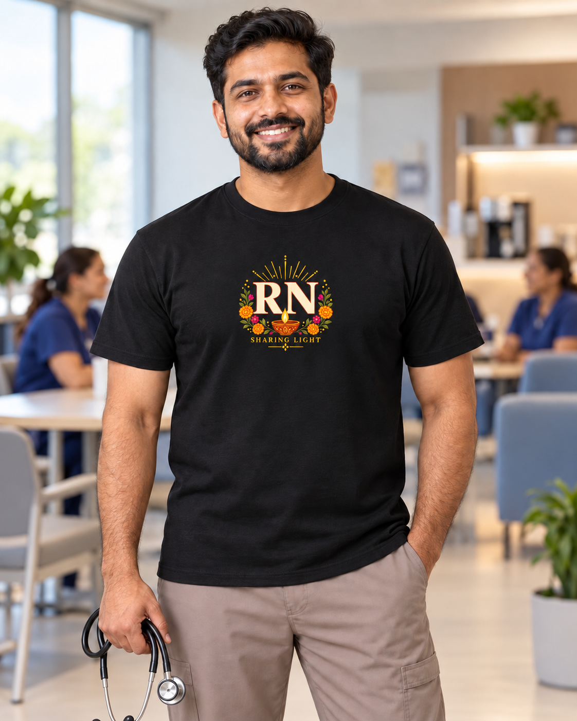 Male nurse wearing a black Nursify RN Diwali T shirt with ivory RN lettering, a diya lamp, colourful flowers and Sharing Light text on the front.