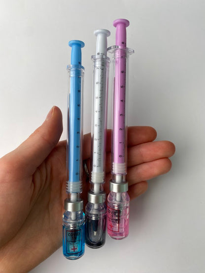 Vial and needle pen in pink, blue and black ink. shown in a had for sizing