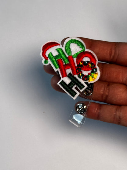 1. Ho Ho Ho. Actual Ho Ho Ho Christmas Badge Reel held in hand; hand shown for visual reference only
