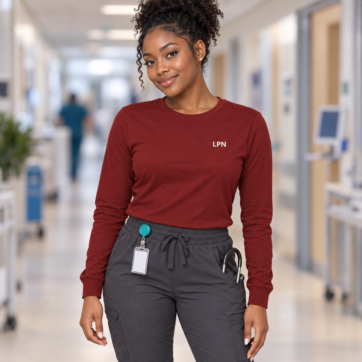 Nurse wearing a cardinal red Nursify LPN long sleeve shirt with charcoal scrub pants.
