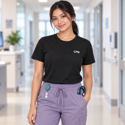 Nurse wearing a black Nursify LPN short sleeve shirt tucked into lilac scrub pants.