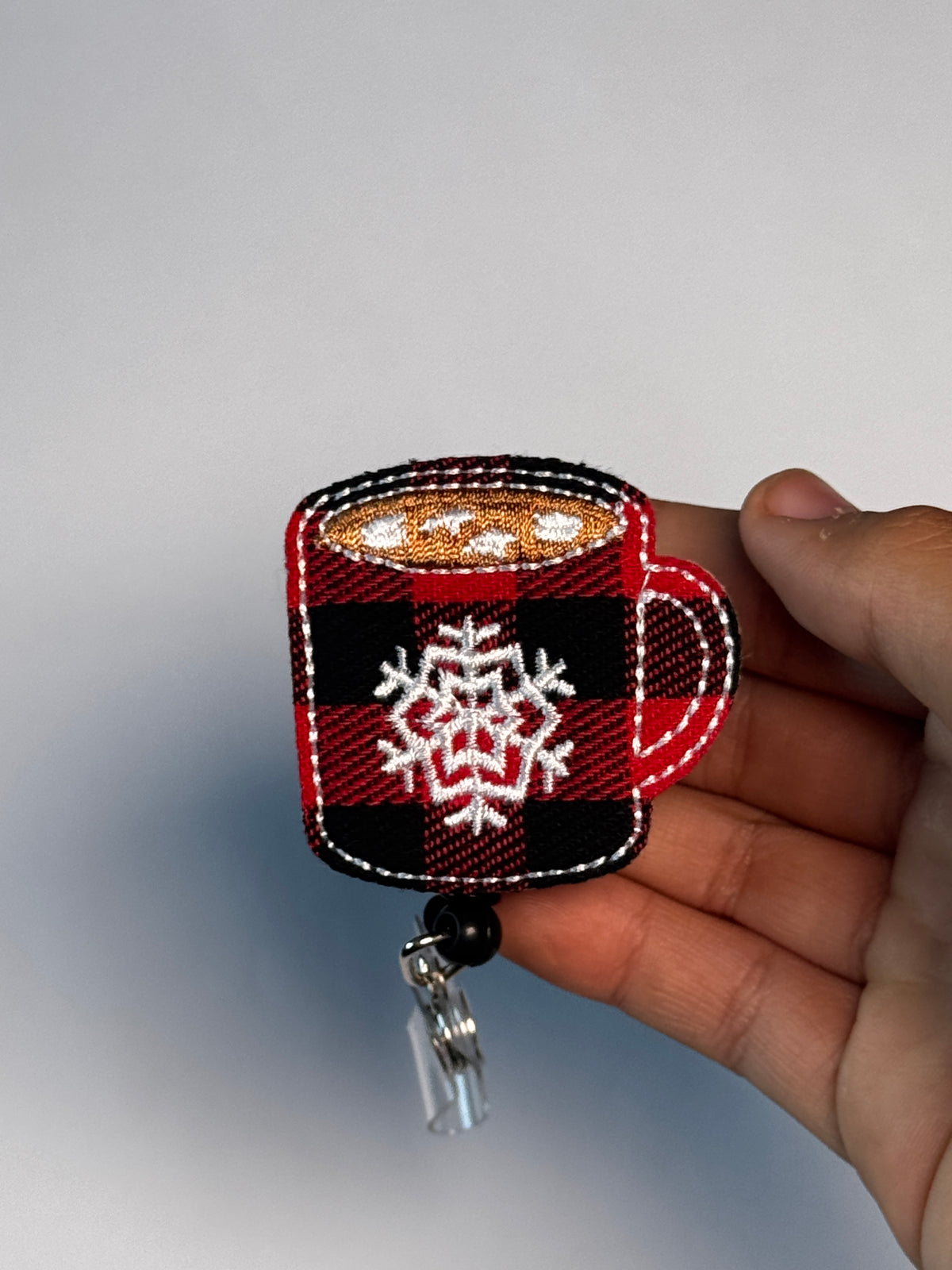 5. Plaid Cocoa Mug. Actual Plaid Mug Christmas Badge Reel held in hand; hand shown for visual reference only