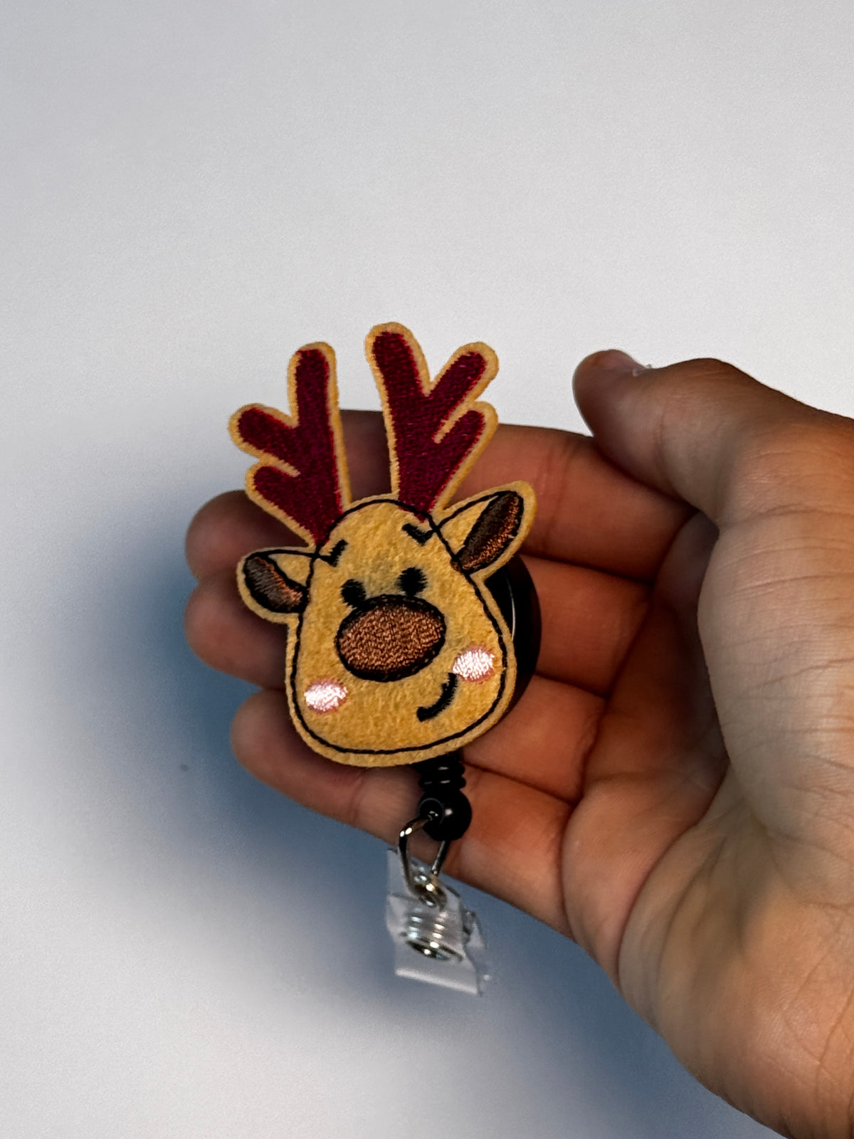 2. Reindeer. Actual Reindeer Christmas Badge Reel held in hand; hand shown for visual reference only