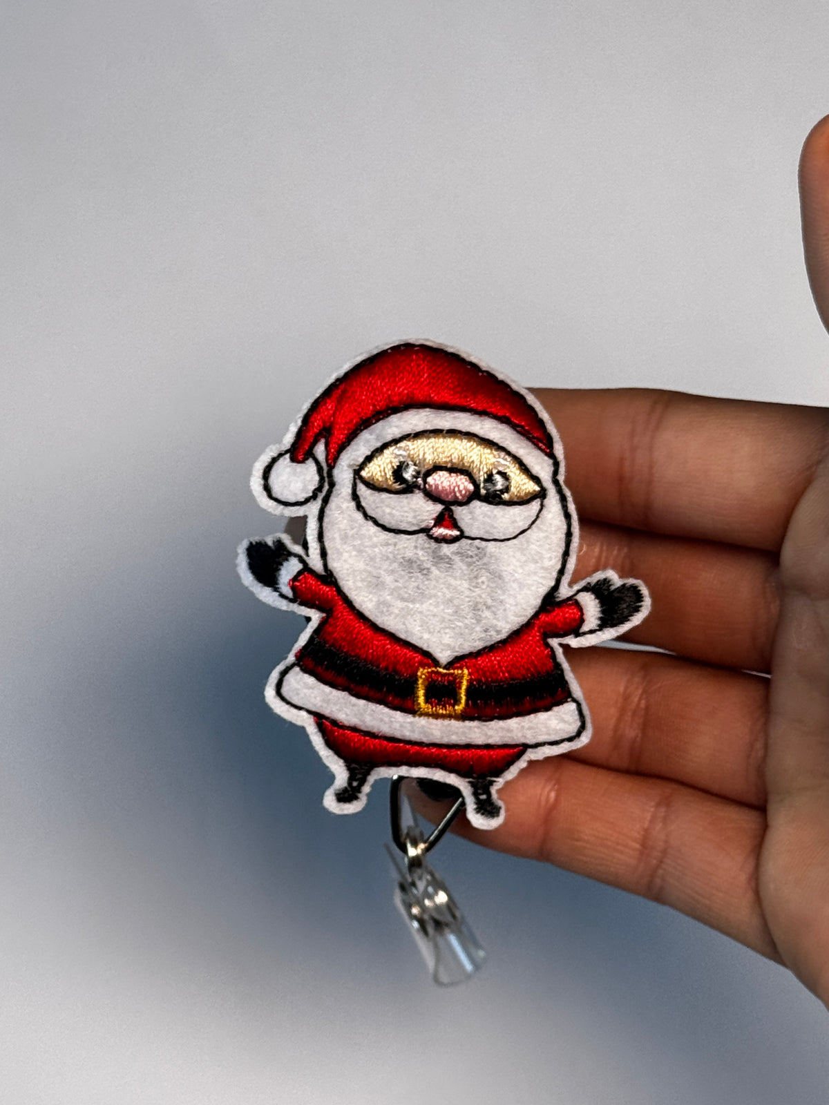 7. Santa. Actual Santa Christmas Badge Reel held in hand; hand shown for visual reference only