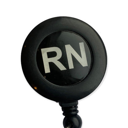 Close-up of two black RN retractable badge reels with white lettering